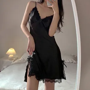 Nuisette sexy en satin noir avec dentelle et fente latérale dans une chambre
