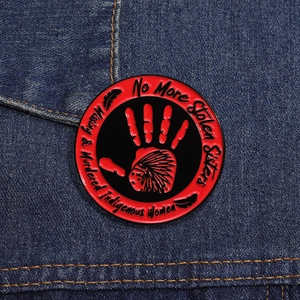 Détail du pin's émaillé empreinte main rouge sur denim avec texte No More Stolen Sisters