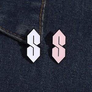 Detailed macro of white and pink enamel S-shaped brooches on denim fabric texture