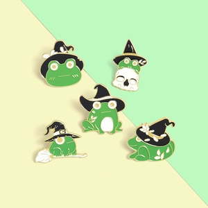 Détail de cinq pin's grenouille sorcière en émail avec crânes et balais sur fond minimaliste