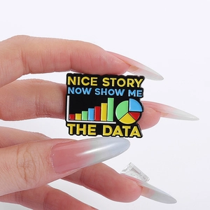 Dettaglio della spilla in smalto con grafici e scritta 'Show me the data' incisa