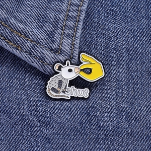 Macro shot of shut possum enamel pin attached to dark blue denim jacket fabric