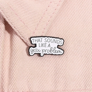 Dettaglio della spilla smaltata 'That sounds like a you problem' su tessuto rosa