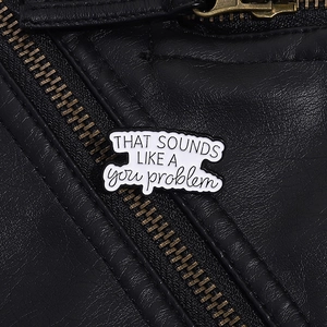Dettaglio di spilla in smalto bianco con testo appuntata su giacca di pelle nera