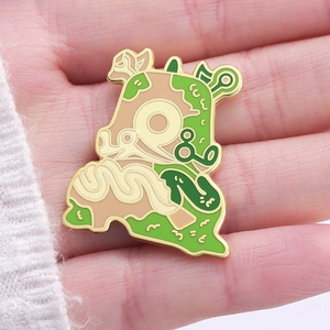 Detailed view of hand-held irregular enamel pin featuring green and gold abstract textures