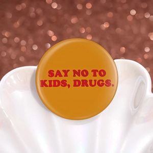 Détail d'un badge rond orange en fer-blanc avec texte rouge sur plateau décoratif blanc