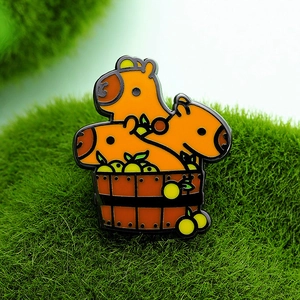 Cute enamel pin featuring three capybaras in a wooden tub bath on green grass