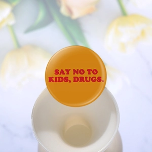 Vue macro d'un badge rond orange avec l'inscription rouge Say No to Kids, Drugs