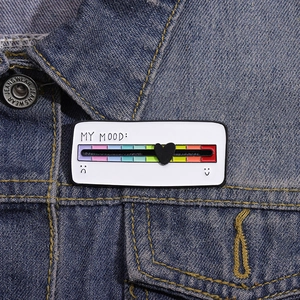Détail de la broche humeur avec cœur coulissant sur rail arc-en-ciel sur veste