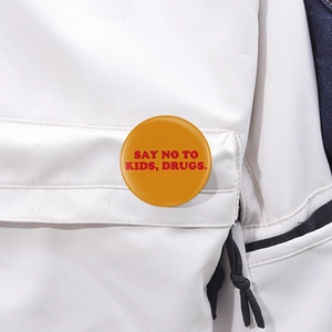 Détail macro du badge rond orange en métal avec slogan sur une veste blanche unie