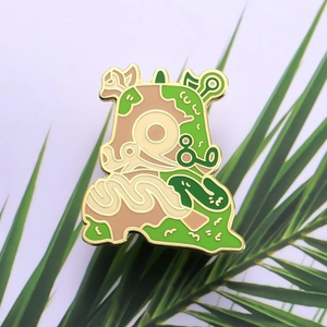 Cartoon enamel pin of a forest creature with green earth tones and gold plated metal edges
