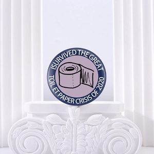 Détail macro du badge humoristique crise du papier toilette sur socle blanc