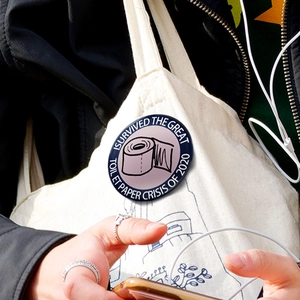 Gros plan d'un badge humoristique de crise du papier toilette sur un sac en toile