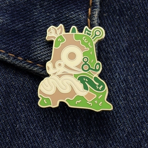 Macro shot of a cartoon monster enamel pin with gold metal edges on blue denim fabric