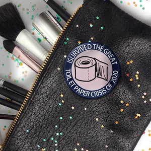 Gros plan du badge drôle sur la crise du papier toilette fixé sur un sac en cuir noir