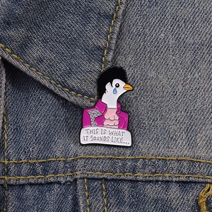 Detail of creative enamel pigeon brooch featuring purple jacket and song lyric text