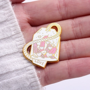 Macro detail of enamel heart tea bag pin with LOVE engraving on a hand palm
