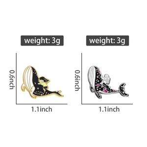 Detail showing dimensions of two enamel whale pins with galaxy and astronaut patterns