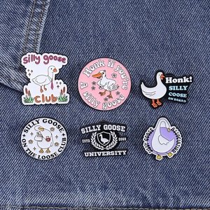 Set of six cute cartoon goose enamel pins displayed on blue denim fabric background