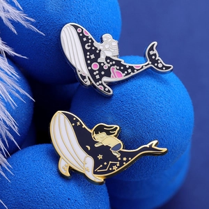 Dreamy whale enamel brooches with astronaut and girl designs on dark blue textured props