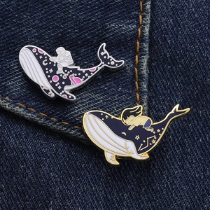 Detailed close-up of astronaut and girl on celestial enamel whale pins on denim jacket