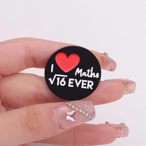 Close-up of heart maths formula enamel pin held by fingers showing actual size