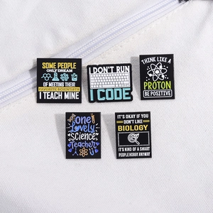 Set of 5 enamel pins with science and coding slogans on white canvas bag background