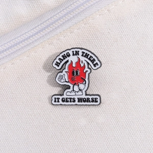 Creative enamel metal pin featuring a cartoon flame giving a thumbs up with hang in there text