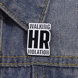 Detail of metal enamel pin with 'WALKING HR VIOLATION' text on a denim jacket