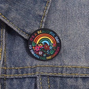 Detail of round enamel pin with rainbow floral pattern on blue denim jacket fabric