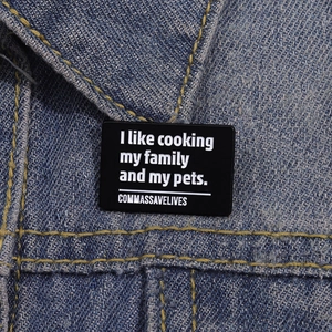 Black enamel pin with grammar joke on blue denim jacket, rectangular metal badge