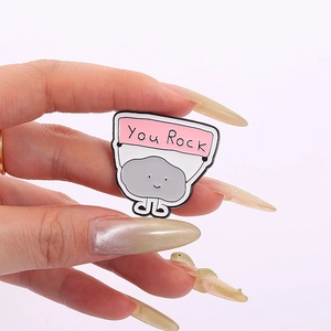 Gros plan d'un badge émaillé mignon en forme de pierre avec bannière You Rock rose