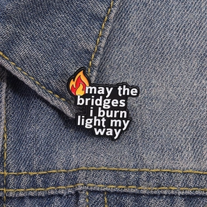 Cartoon-Emaille-Pin mit Zitat und Flammen-Detail an einem blauen Jeansjackenkragen
