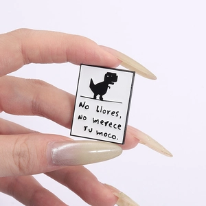 Minimalist enamel dinosaur pixel pin with Spanish quote on white metal badge background