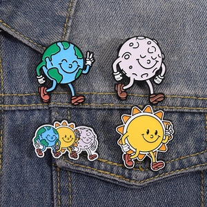 Lot de quatre broches en émail dessin animé Terre Soleil et Lune sur denim