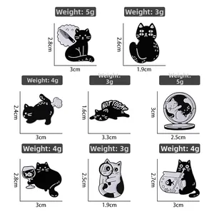 Vue détaillée des broches chat en émail noir et blanc avec dimensions et poids