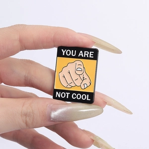 Cartoon enamel pin with hand gesture and text YOU ARE NOT COOL in yellow rectangle