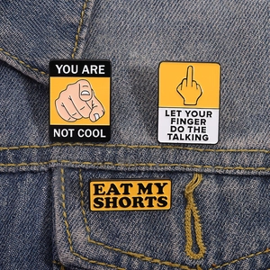 Three custom slogan enamel pins with gestures on blue denim fabric background