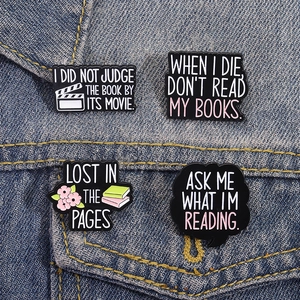 Set of four cartoon book quote enamel pins displayed on a blue denim jacket pocket