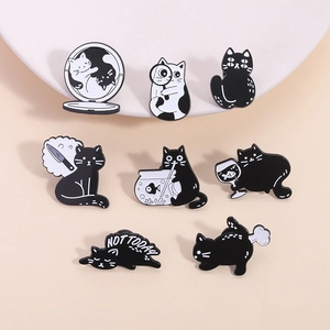 Vue macro détaillée de broches de chat en émail noir et blanc sur un plateau en céramique
