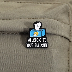 Creative enamel pin tissue box shape with Allergic To Your Bullshit quote on a backpack