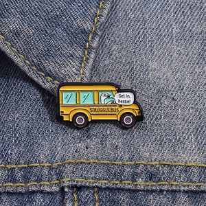 Gros plan sur le pin's Struggle Bus avec oie de dessin animé sur col de veste denim