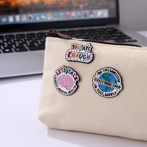 Mental health enamel pins set with motivational quotes on a canvas storage bag