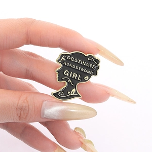 Black and gold enamel pin featuring a girl silhouette with Obstinate Headstrong Girl quote