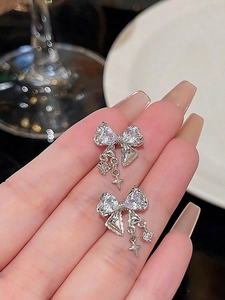 Détail de boucles d'oreilles nœud argentées avec oxydes de zirconium et étoiles