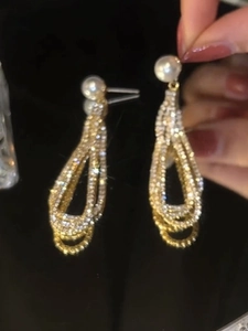 Détail de boucles d'oreilles longues avec cristaux brillants et une perle blanche