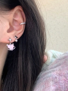 Close-up of pink heart star earrings set and zircon ear cuff worn by a female model