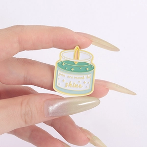 Detailed view of enamel candle pin featuring you are meant to shine golden text