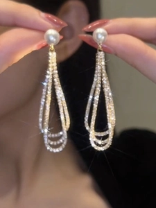 Vue détaillée de longues boucles d'oreilles à pompons avec perles et cristaux