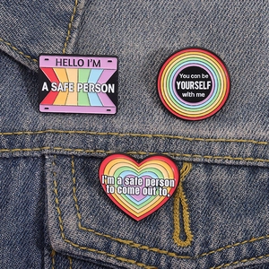 Rainbow pride enamel pins set with inspirational quotes on a blue denim jacket pocket